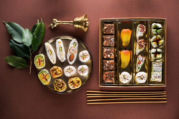 Indian candies sweets and Mithai in a box, insense sticks and Aladdin lamp. Diwali festival...