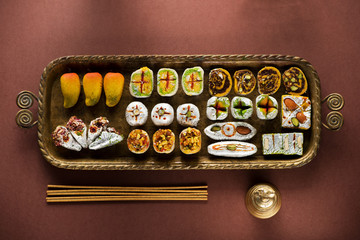 Indian sweets and Mithai in a tray, incense and bell for Diwali festival, flat lay, top view