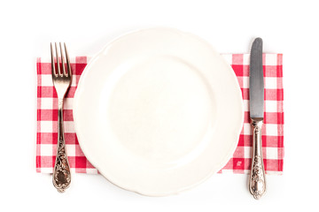An overhead photo of a white plate with a fork and a knife on a white background with copy space