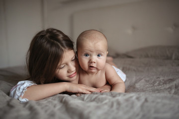 older sister and naked baby 5 months on bed