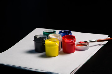 Multicolored cans of gouache with Paintbrush