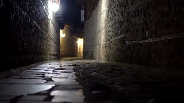 Move POV at mysterious narrow alley with stone pavement lanterns at night