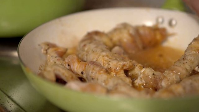 Juicy roasted chicken skewers, made of white meat and bacon, being turned in frying pan