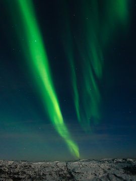 Beautiful stripes of the northern lights, aurora in the night sky above the hills.