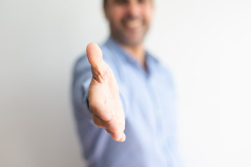 Closeup of business man offering hand for handshake. Entrepreneur greeting you. Deal concept. Cropped front view.
