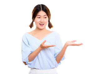 Studio shot of young happy Asian woman smiling while showing som