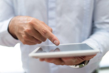 Close-up of marketing specialist analyzing data online while using digital tablet. Unrecognizable businessman pointing at gadget display. Information concept