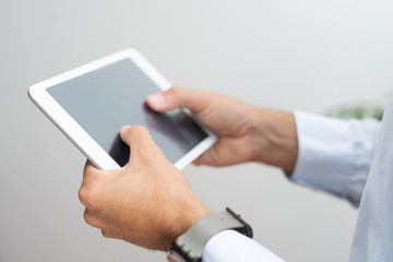 Close-up of unrecognizable man zooming in picture while using digital tablet. Businessman working with online data on gadget. Wifi concept