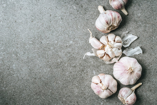Top view of garlic bulbs and husk on grey background with copy space