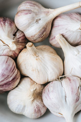 close up of ripe garlic heads in white ceramic bowl