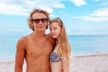 Smiling playful young couple in love having fun at sandy beach.