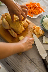 Female hands preparing raw chicken on wooden cutting board, close-up