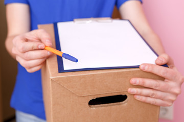 Photo close up of courier with pen, blank sheet of paper, cardboard box