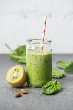 Kiwi, spinach leaves and green organic smoothie in glass with straw