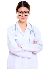 Studio shot of young beautiful Asian woman doctor with arms cros