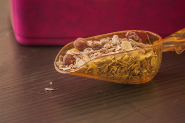Fototapeta na wymiar Scoop with dry oatmeal and nuts on wooden background, close-up
