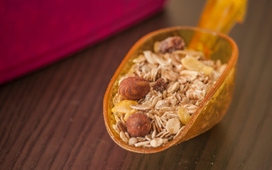 Scoop with dry oatmeal and nuts on wooden background, close-up