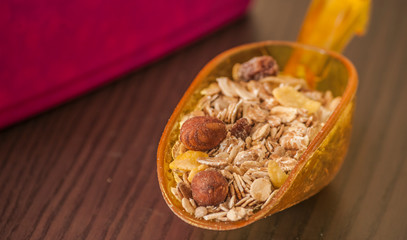 Scoop with dry oatmeal and nuts on wooden background, close-up
