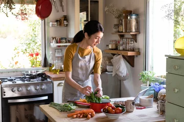 Crédence de cuisine en verre imprimé Cuisinier Femme asiatique occupée à cuisiner dans la cuisine