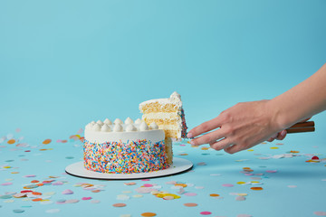 Partial view of woman taking piece of delicious cake on blue background