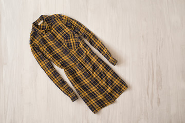 Yellow chekcered shirt on wooden background. Fashionable concept