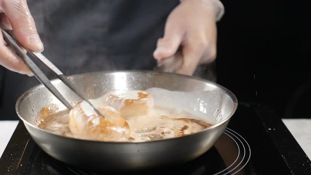 Chef cooking. Cooker in gloves prepares seafood. Boiling scallops in cream sauce in frying pan. hd