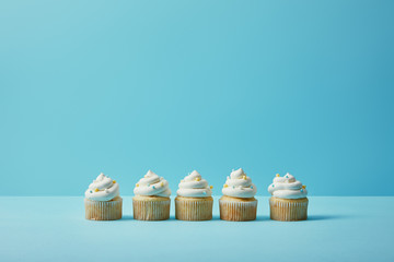 Delicious cupcakes with sugar sprinkles on blue background