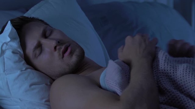 Young male having anxiety dreams, talking in sleep after long stressful workday