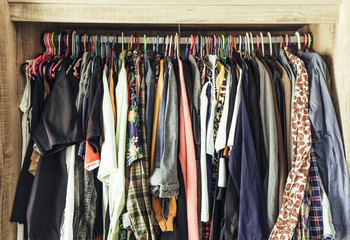 Hangers with different clothes in wardrobe closet
