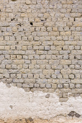 Old vintage grey brick wall with traces of white plaster