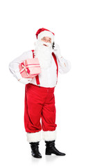 santa claus in suspenders holding gift box and talking by phone isolated on white