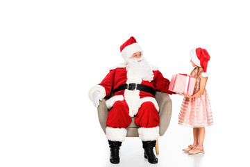 santa claus sitting in armchair and giving present to little child isolated on white