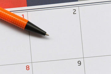 Orange pen points to a empty area on the calendar background of 2nd day for design in your work concept.