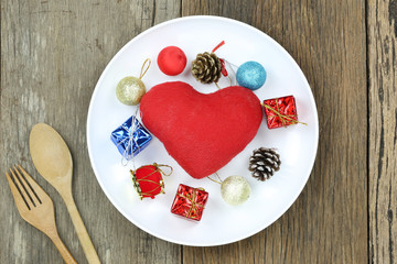 Christmas Decoration with Red heart in white dish on wooden floor.