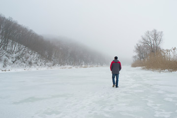 Fototapeta na wymiar A man walks on a frozen river in winter.