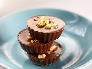 Milk chocolate cup candys with pistachio on the blue plate