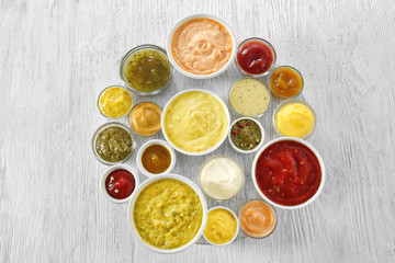 Different tasty sauces in bowls on white wooden table