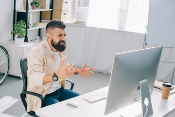 successful businessman actively gesticulating at desk in modern office