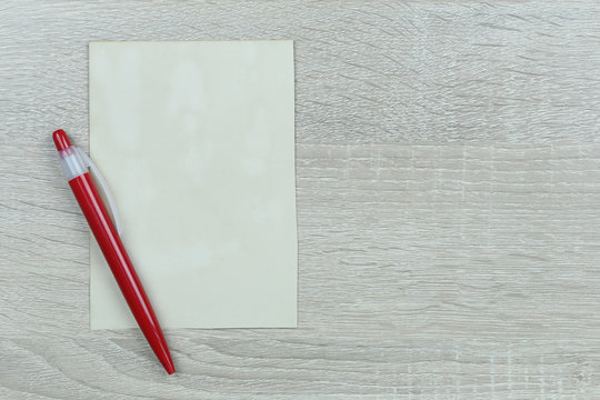 Red Pen Placed Next To Vintage Paper On Wooden Floor.