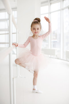 Little ballerina girl in a pink tutu. Adorable child dancing classical ballet in a white studio. Children dance. Kids performing. Young gifted dancer in a class. Preschool kid taking art lessons
