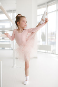 Little ballerina girl in a pink tutu. Adorable child dancing classical ballet in a white studio. Children dance. Kids performing. Young gifted dancer in a class. Preschool kid taking art lessons
