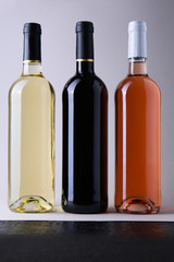 Bottles with different kinds of wine on grey background