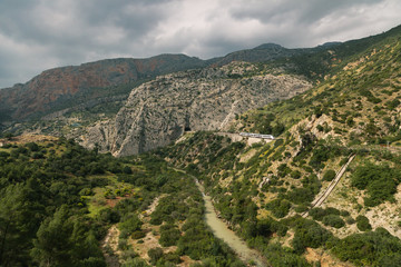 Fototapeta na wymiar Train approaching a tunnel in a large valley in ardales, andalucia, surrounded by hills and a river