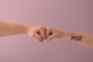 Man and woman making fist bump gesture on color background