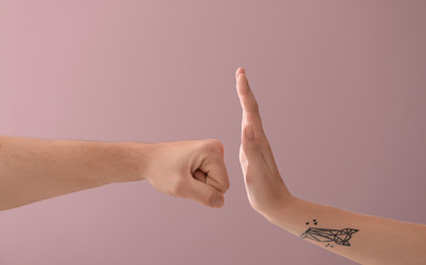 Woman stopping aggressive man on color background