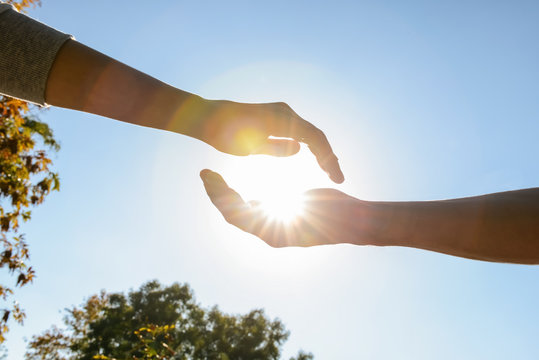 Male and female hands with sun outdoors