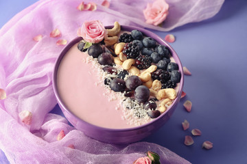 Bowl with pink yogurt, nuts and fresh fruits on color background