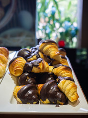 Assortment of delicious and buttery croissants decorated with chocolate icing made by pastry chef. All look very tasty and delightful. Natural light.