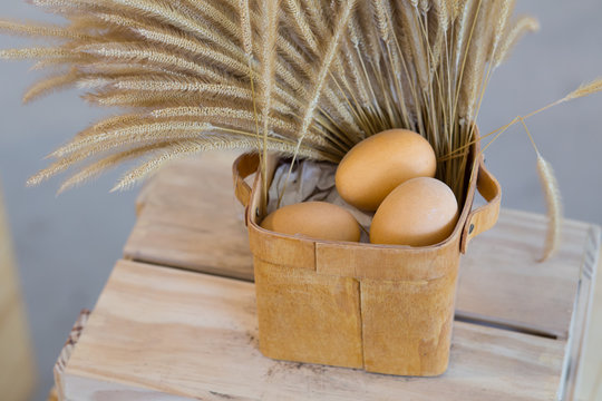 Eggs and dry poaceae in wooden basket.