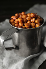 Metal mug with fried chickpeas on table, closeup